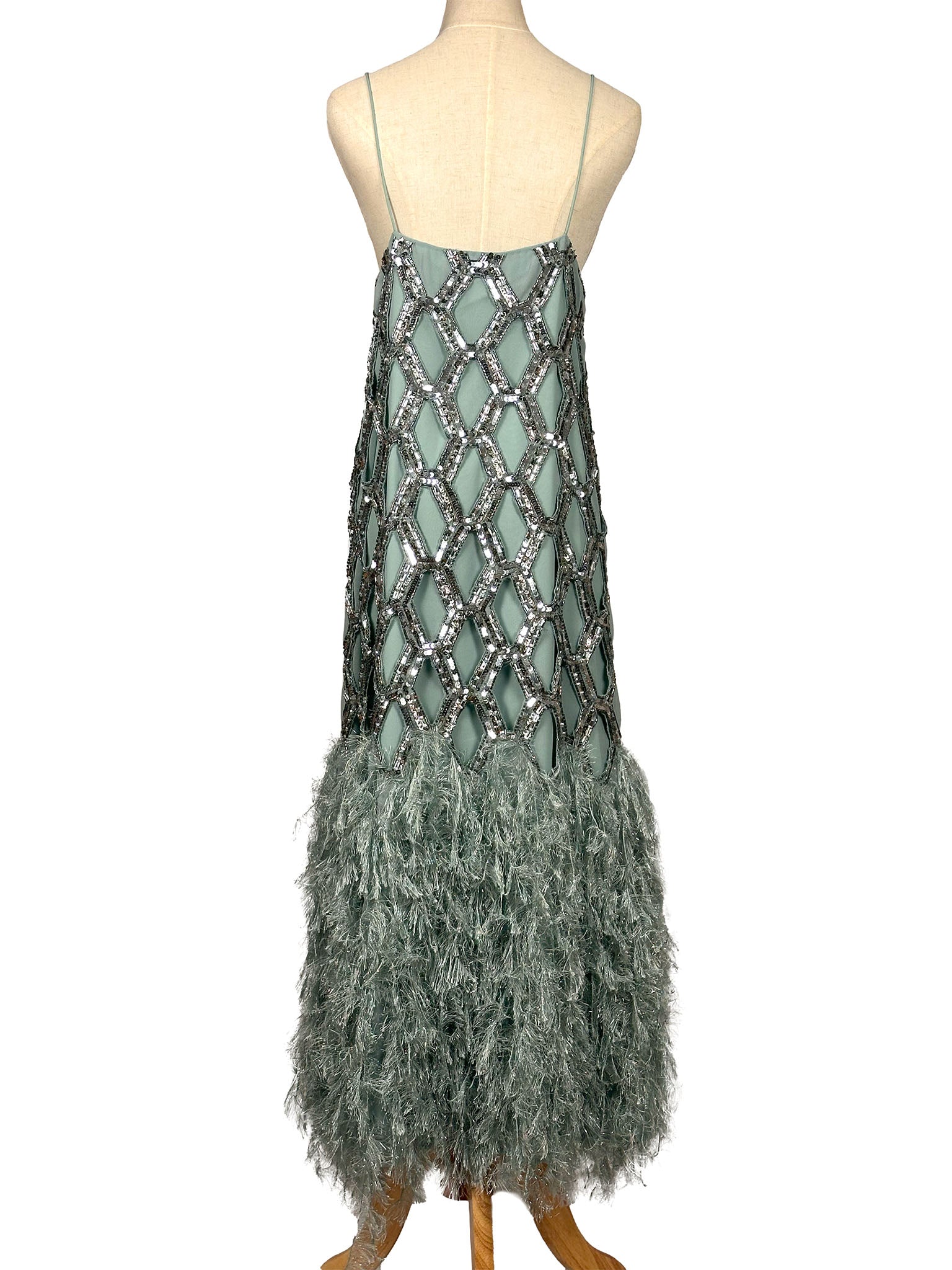 Green dress with feather details on a mannequin against a white background