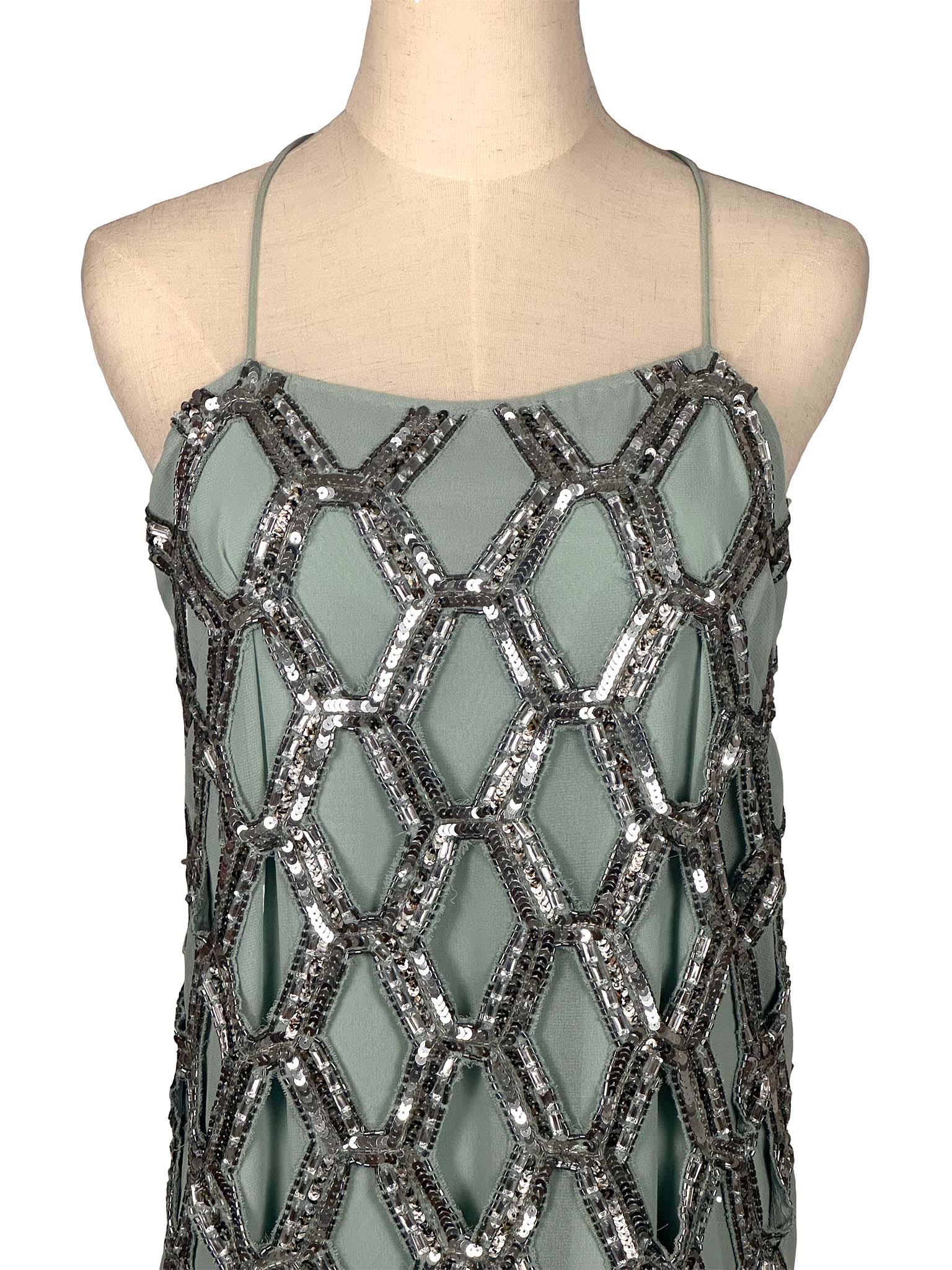 Green dress with silver geometric sequin pattern on a mannequin against a white background