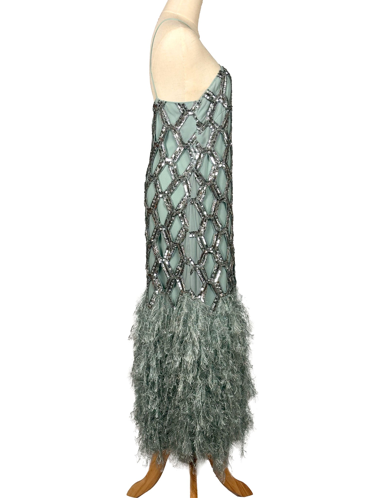 Mannequin wearing a long, elegant dress with sequin detailing and feathered skirt on a white background