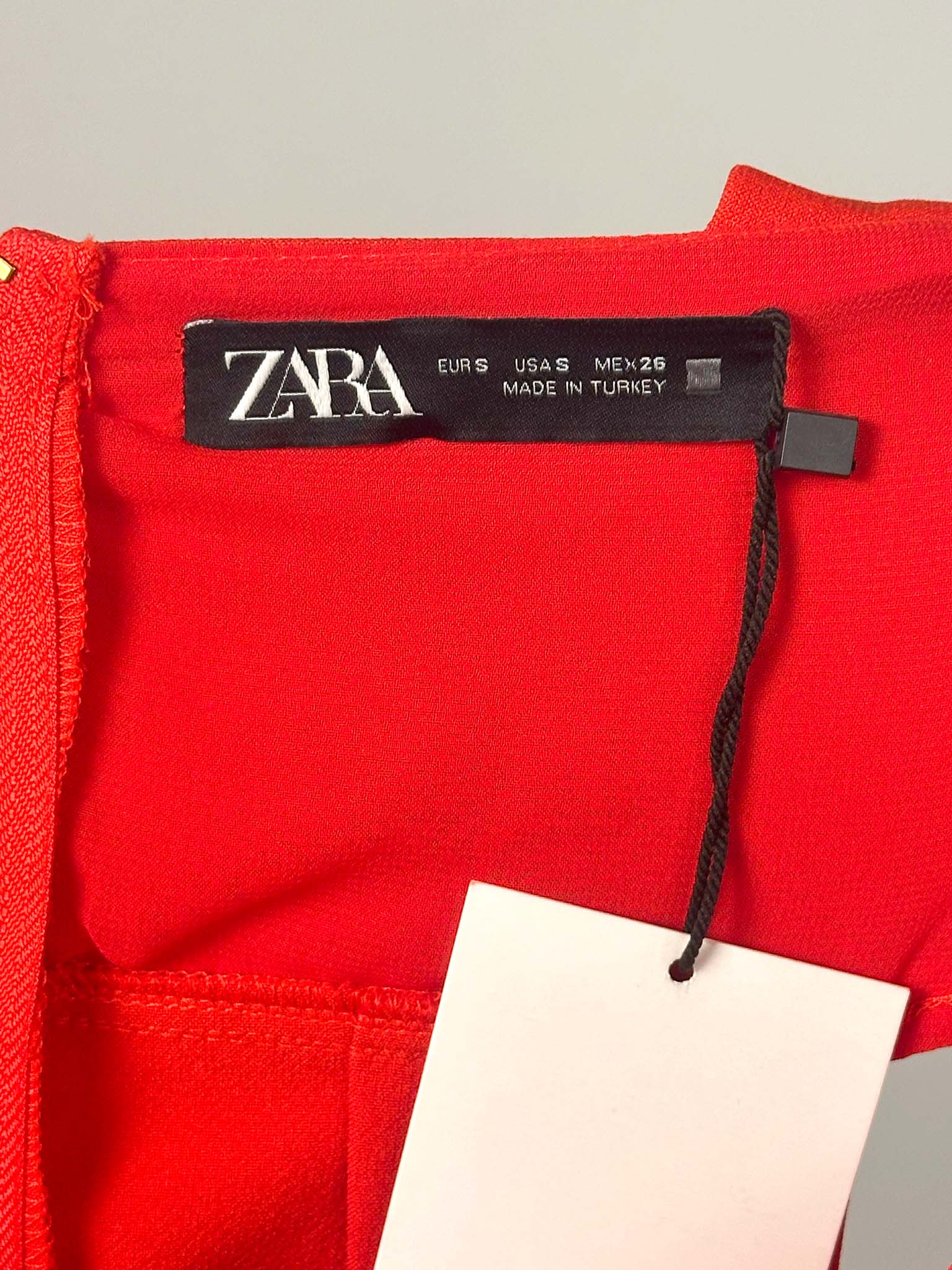 Red garment with a Zara tag on a gray background
