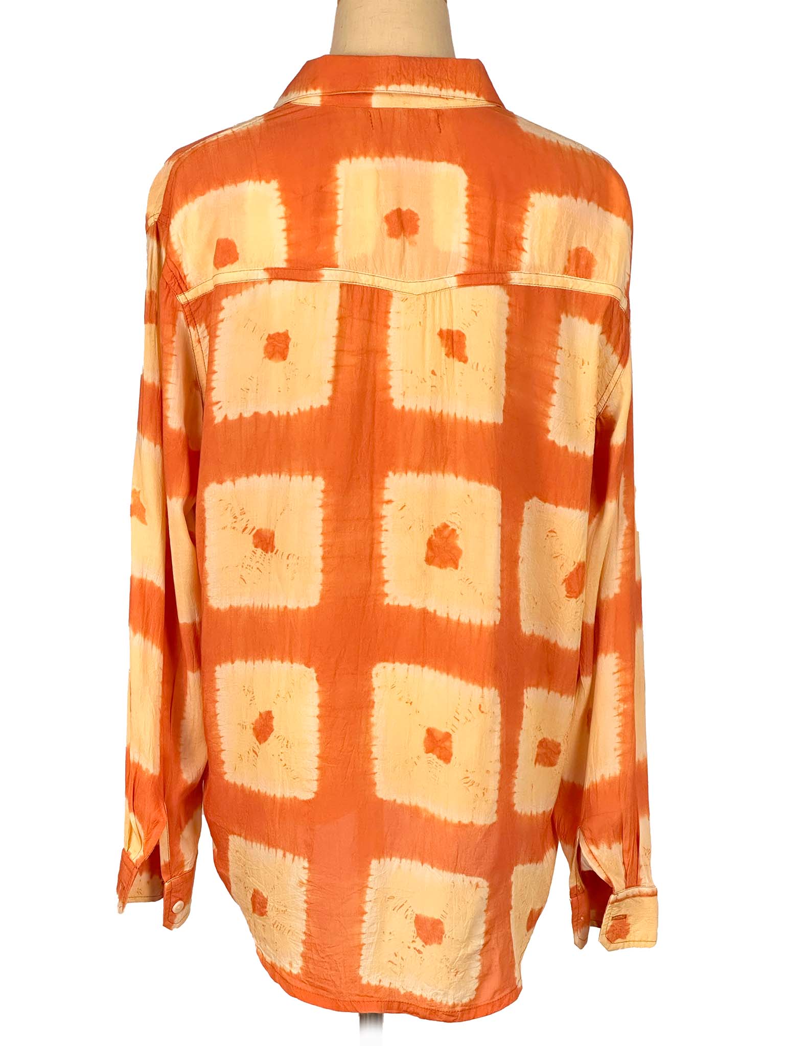 Orange and beige patterned shirt on a mannequin against a white background