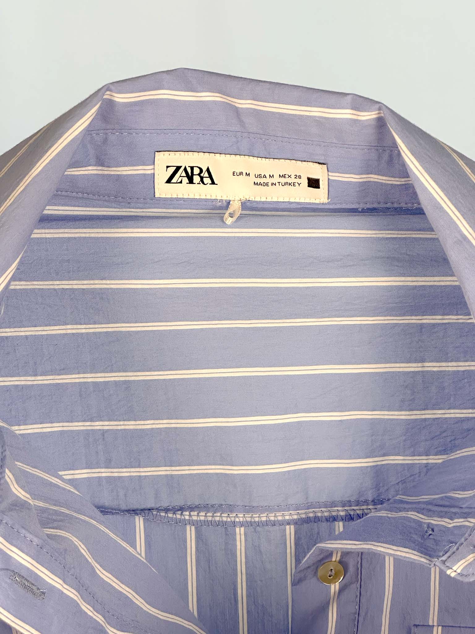 Close-up of a Zara shirt with a visible label on a light gray background