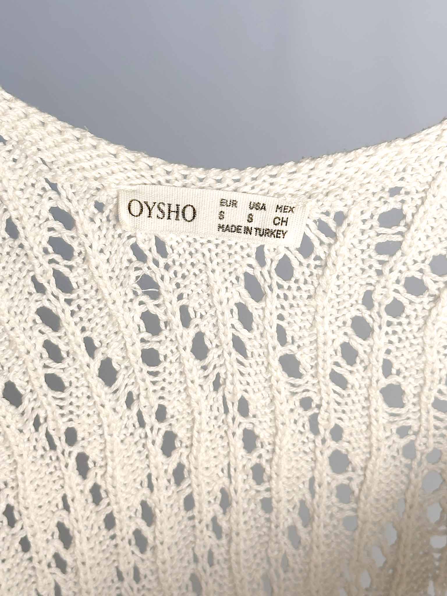 Close-up of a knit garment with 'Oysho' label on a gray background