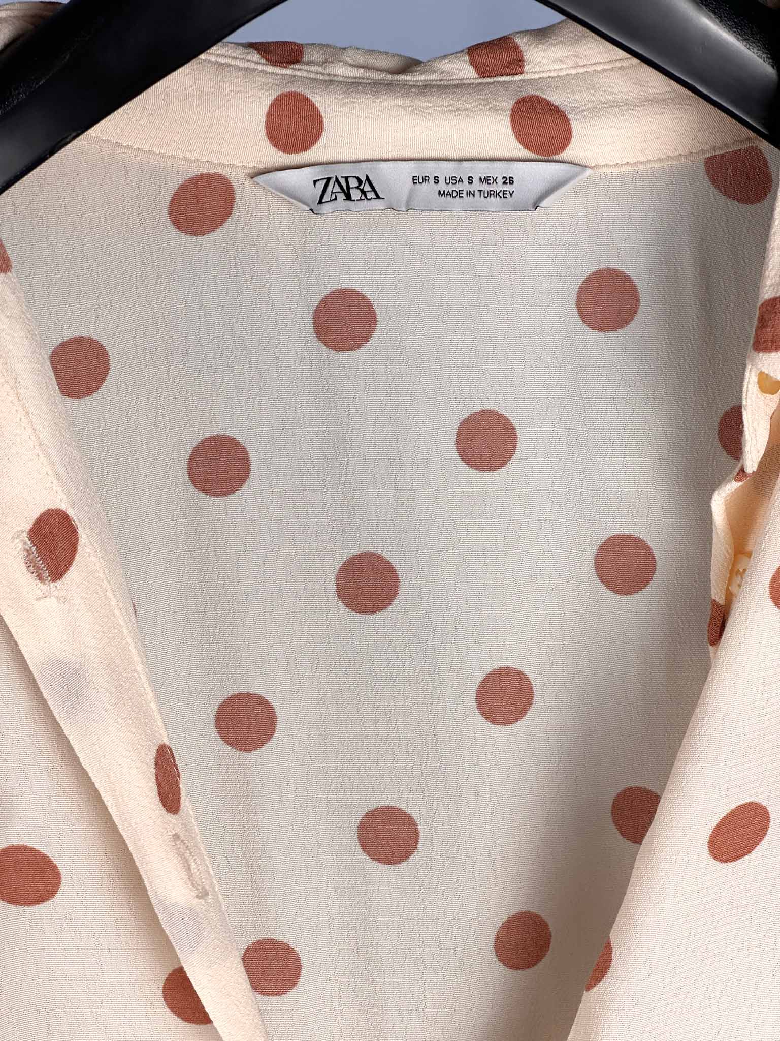 Close-up of a fabric with brown polka dots and Zara label.