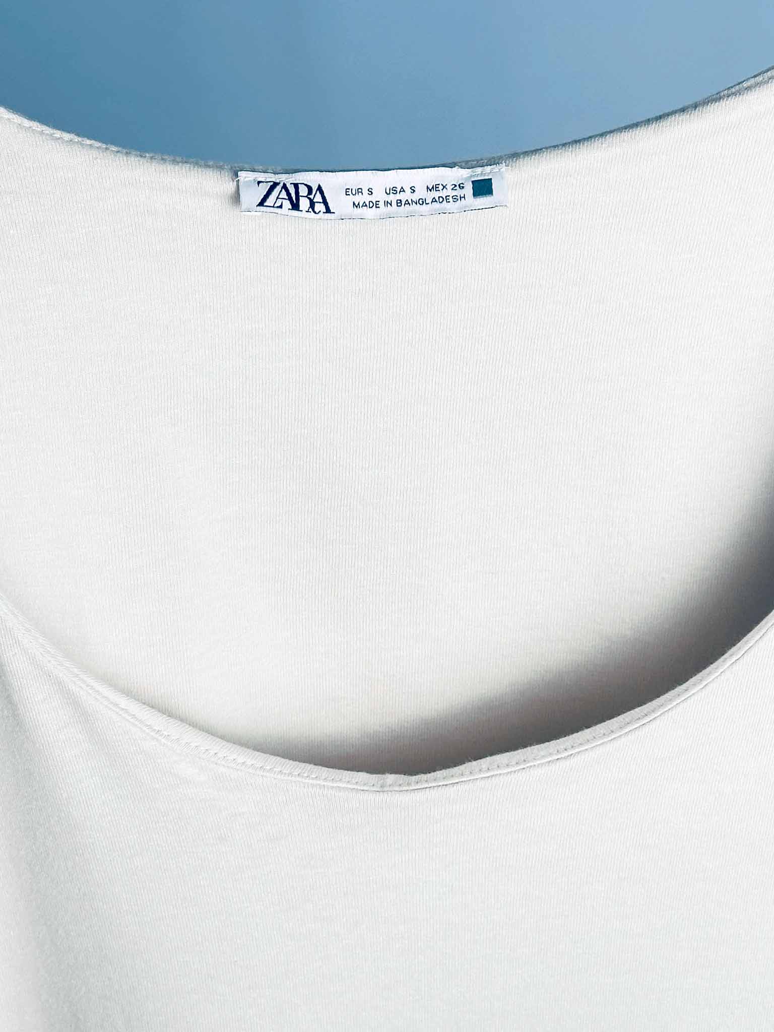 White tank top with Zara label against a blue sky