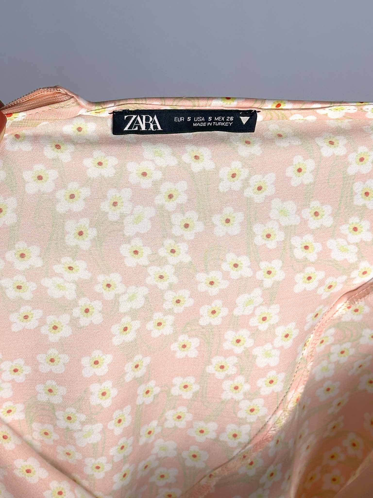 Pink floral patterned fabric with Zara label on a gray background