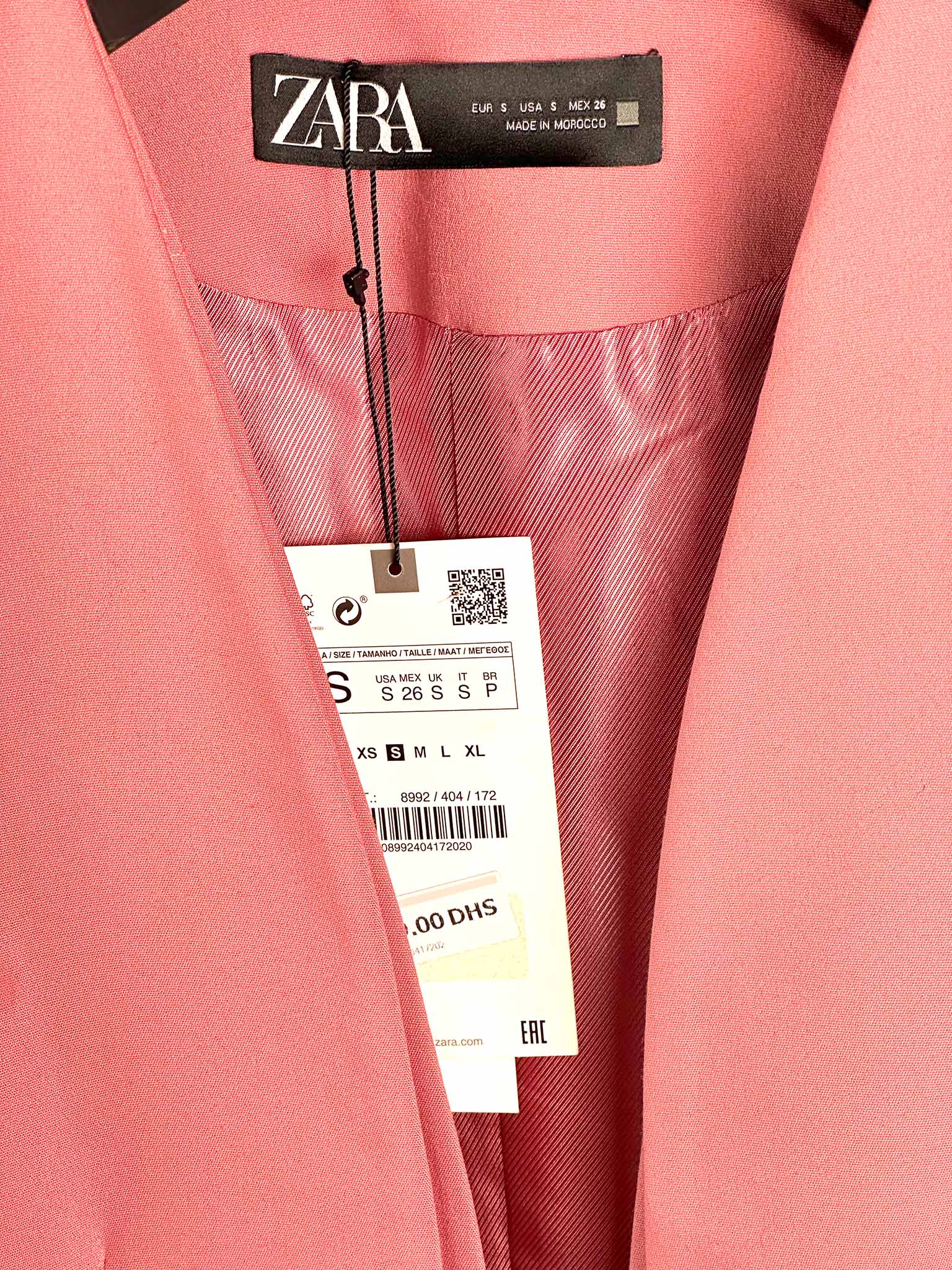 Close-up of a pink garment with Zara label and price tag.