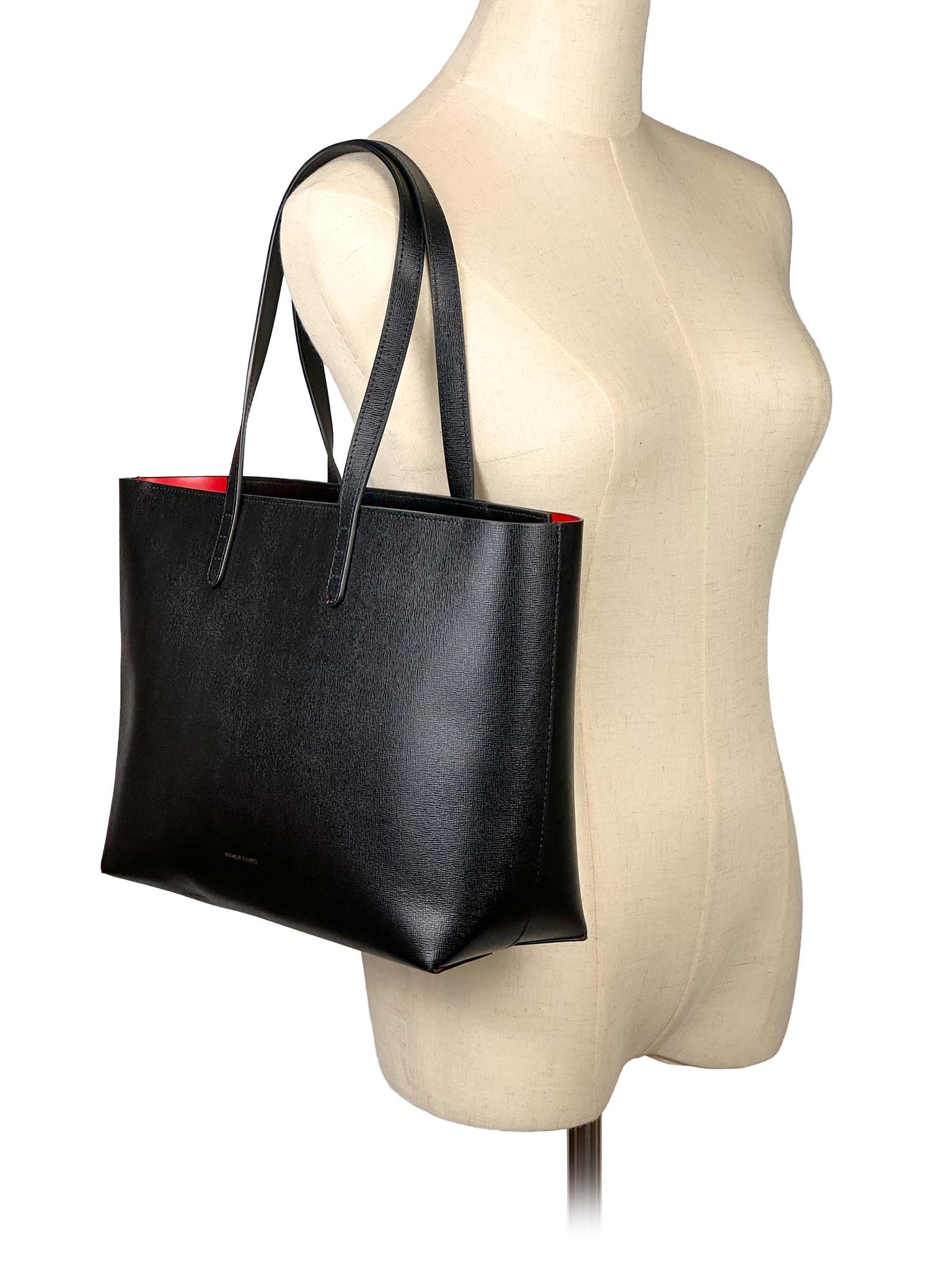 Mansur Gavriel  black tote bag on a mannequin with a white background
