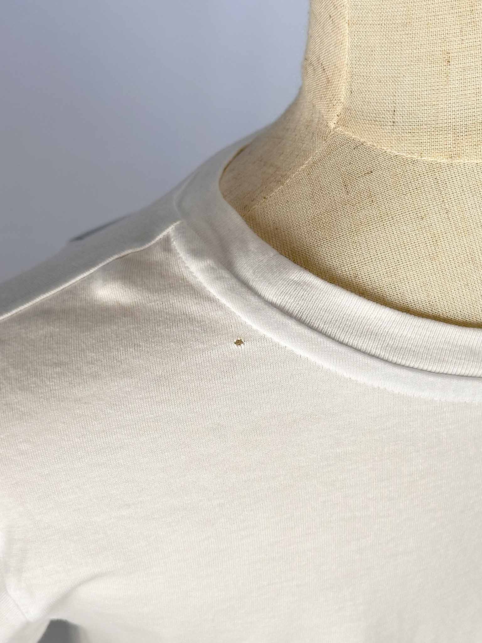 Close-up of a white shirt with a small hole on a neutral background