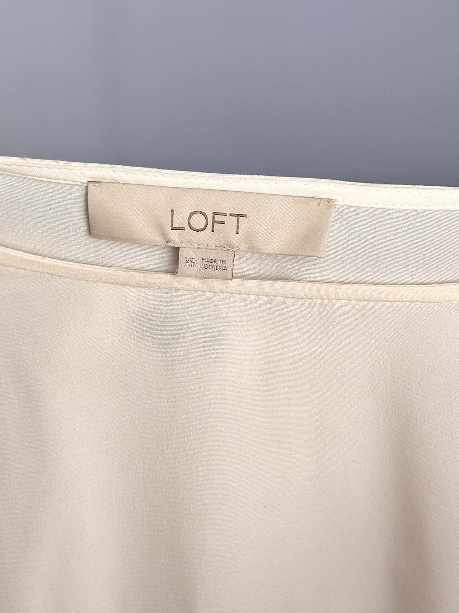 Beige pants with a LOFT label on a gray background