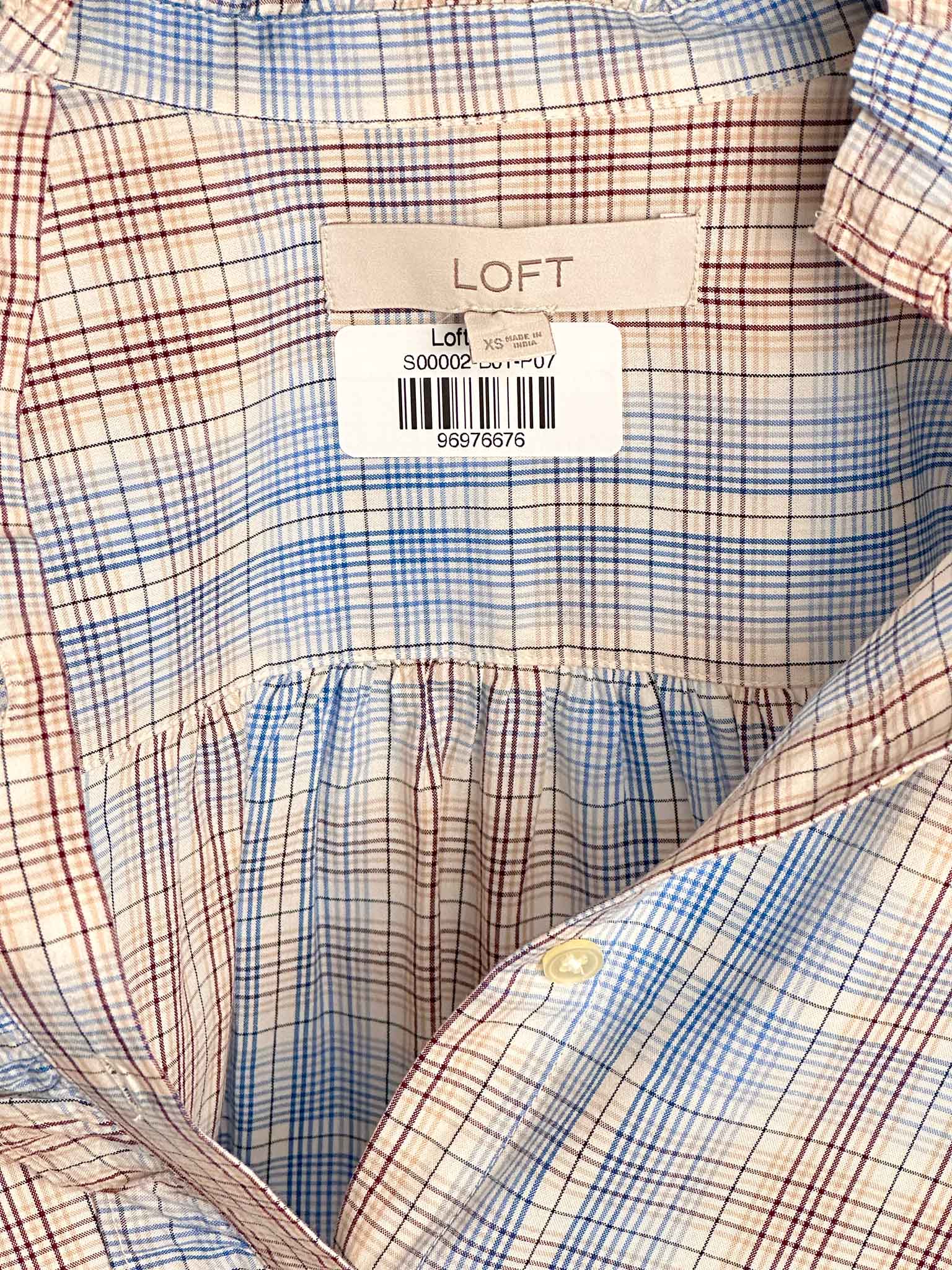 Close-up of a plaid shirt with a LOFT label on a checkered background