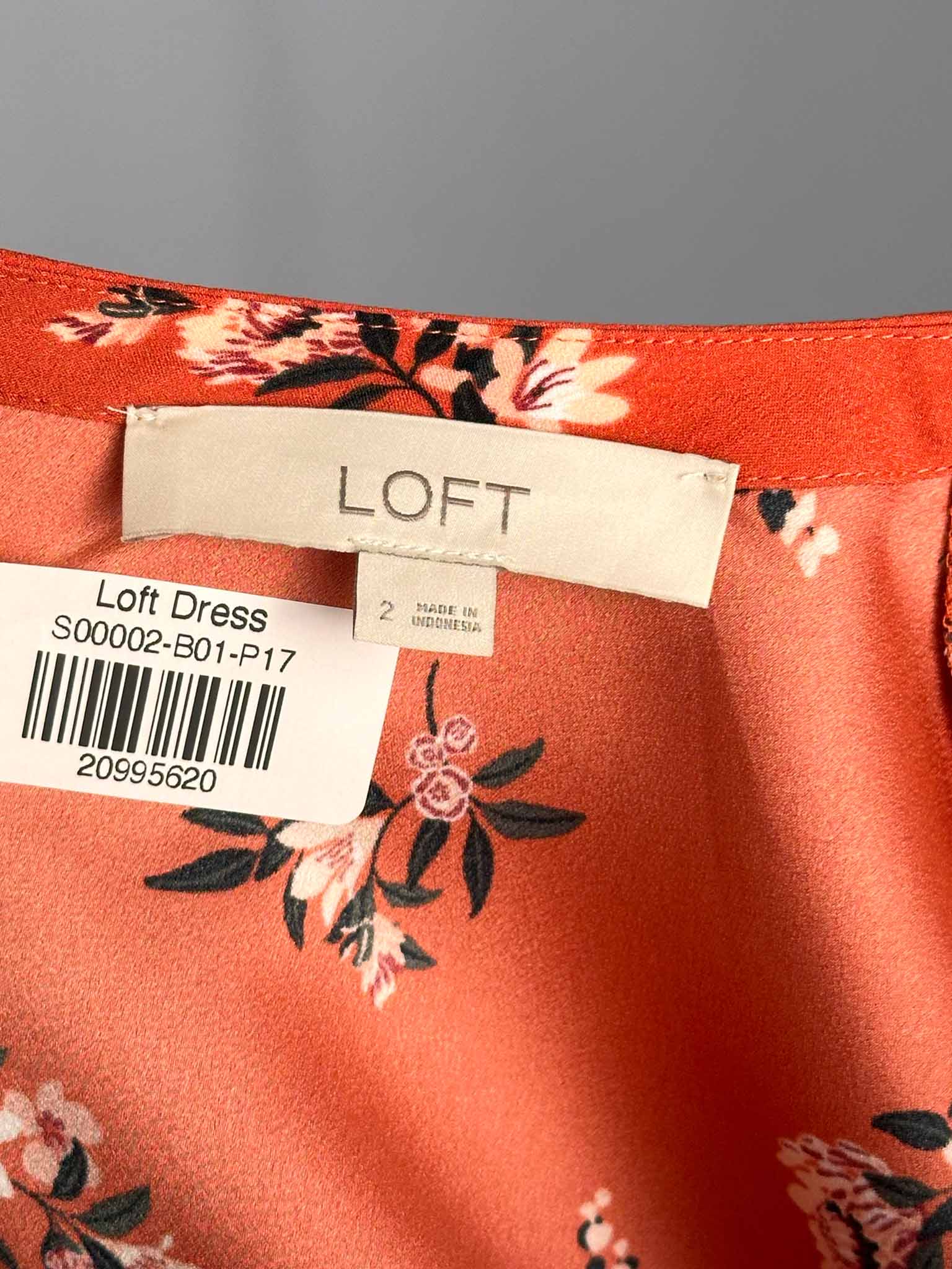Red dress with floral patterns and a LOFT label on a gray background