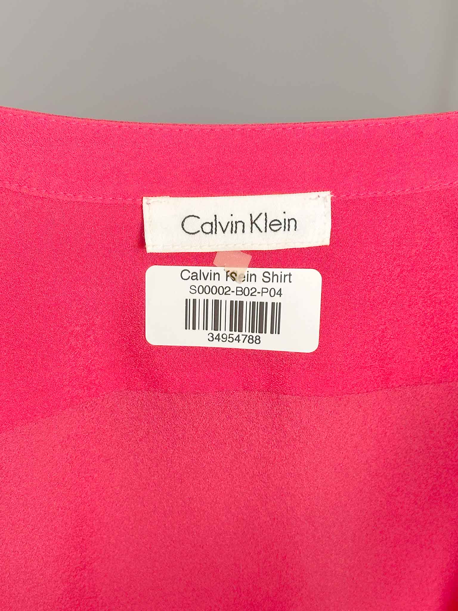 Calvin Klein label on a pink shirt with a gray background