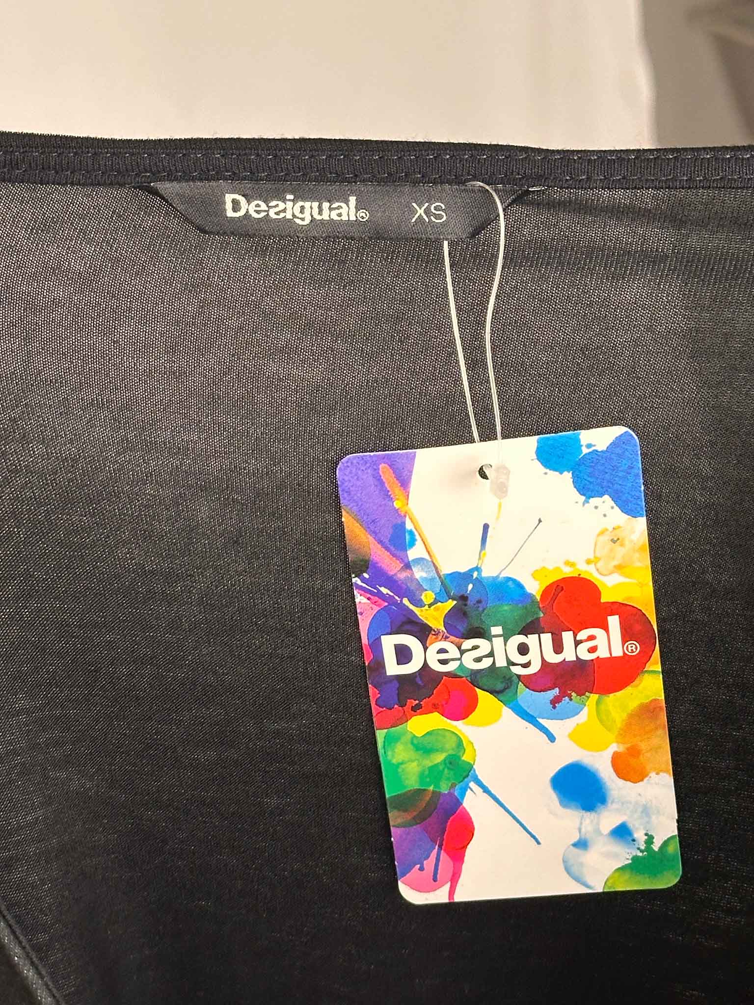 Gray garment with a colorful Desigual tag on a white background