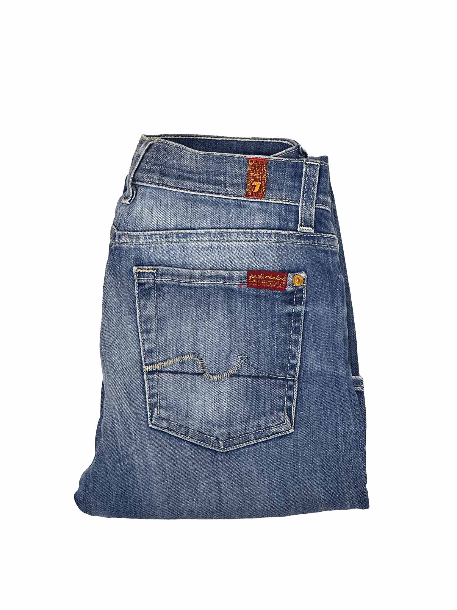 Folded blue denim jeans with a brand label on a white background