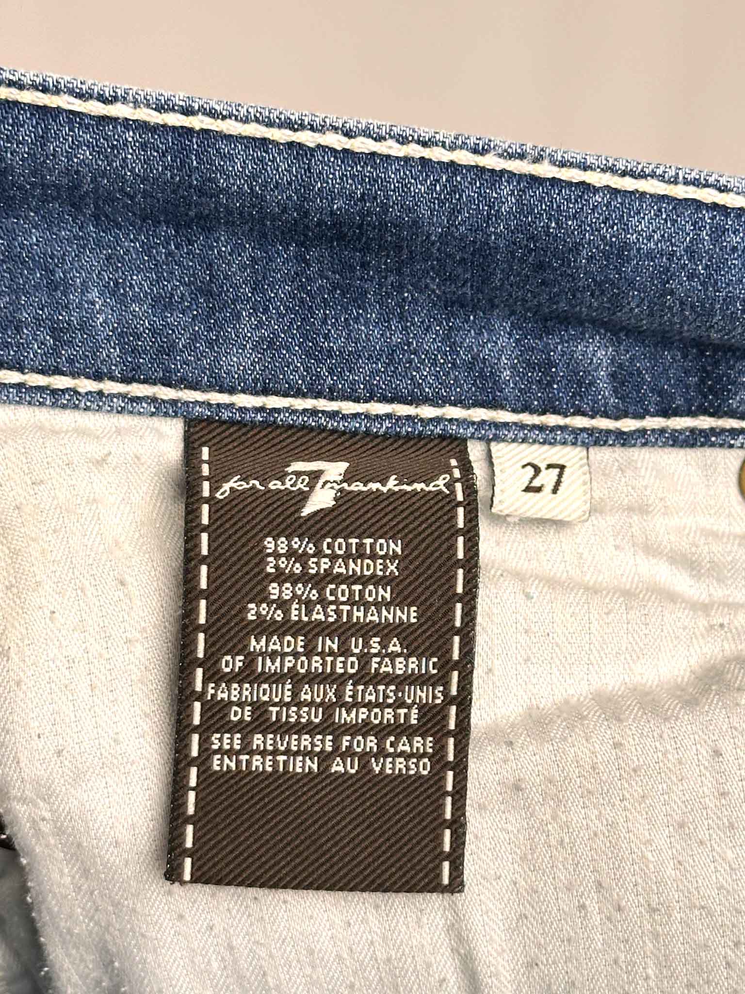 Close-up of a 7 For All Mankind jeans label with size and fabric information.