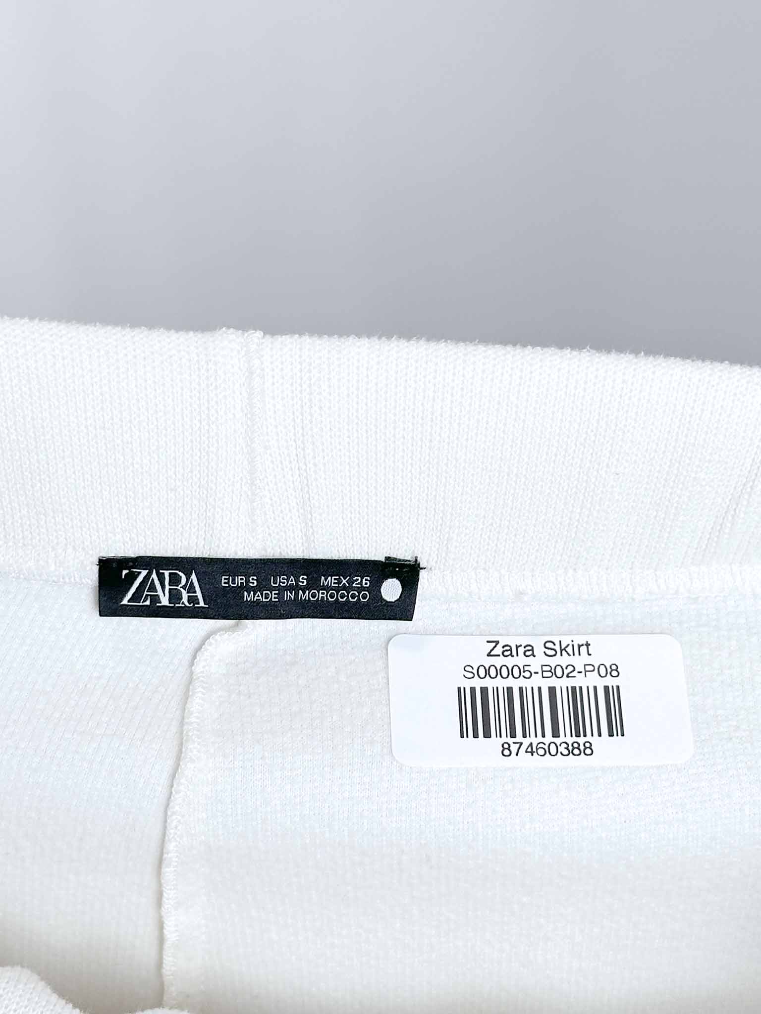 Zara label on a white skirt with a gray background