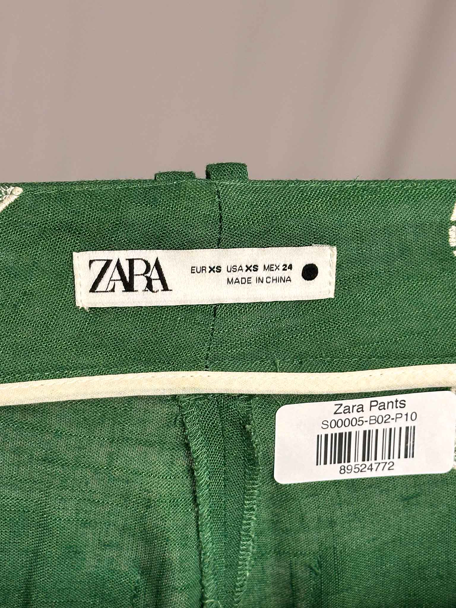 Green Zara pants with a label on a gray background