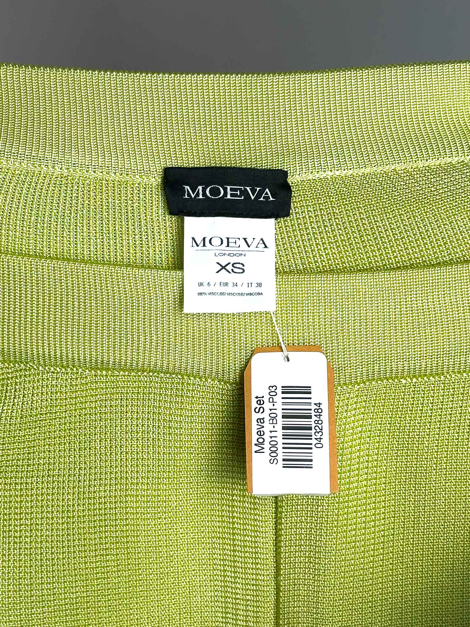 Green fabric pants with MOEVA label and XS size tag on a gray background