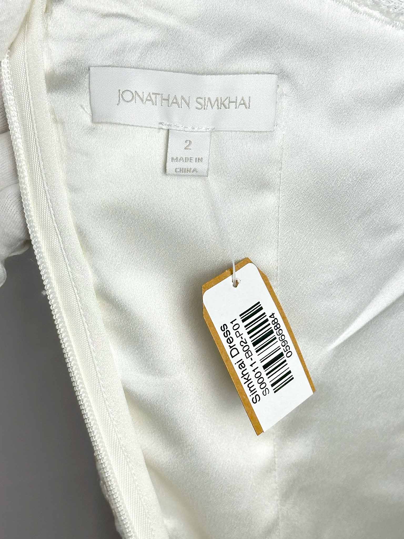 Close-up of a white garment with a label displaying 'Jonathan Simkhai' and size information.