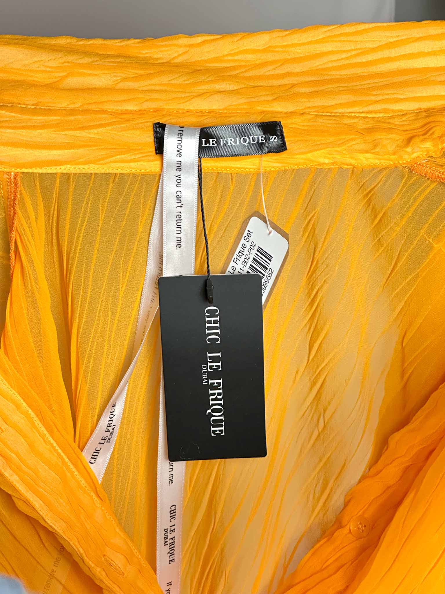Close-up of a yellow fabric with 'Chic Le Frieque' tags.