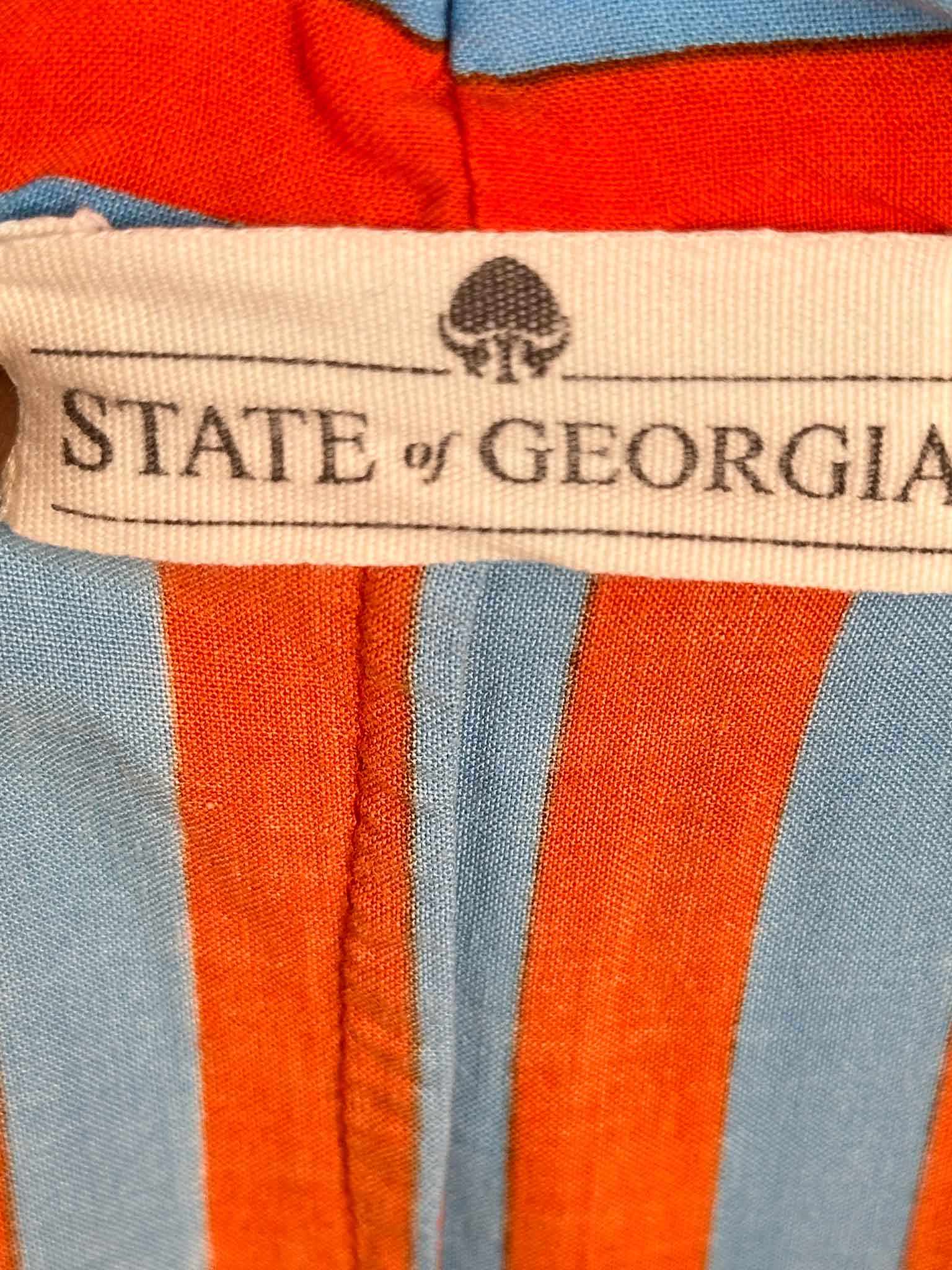 Close-up of a fabric with 'State of Georgia' label on orange and blue striped material.