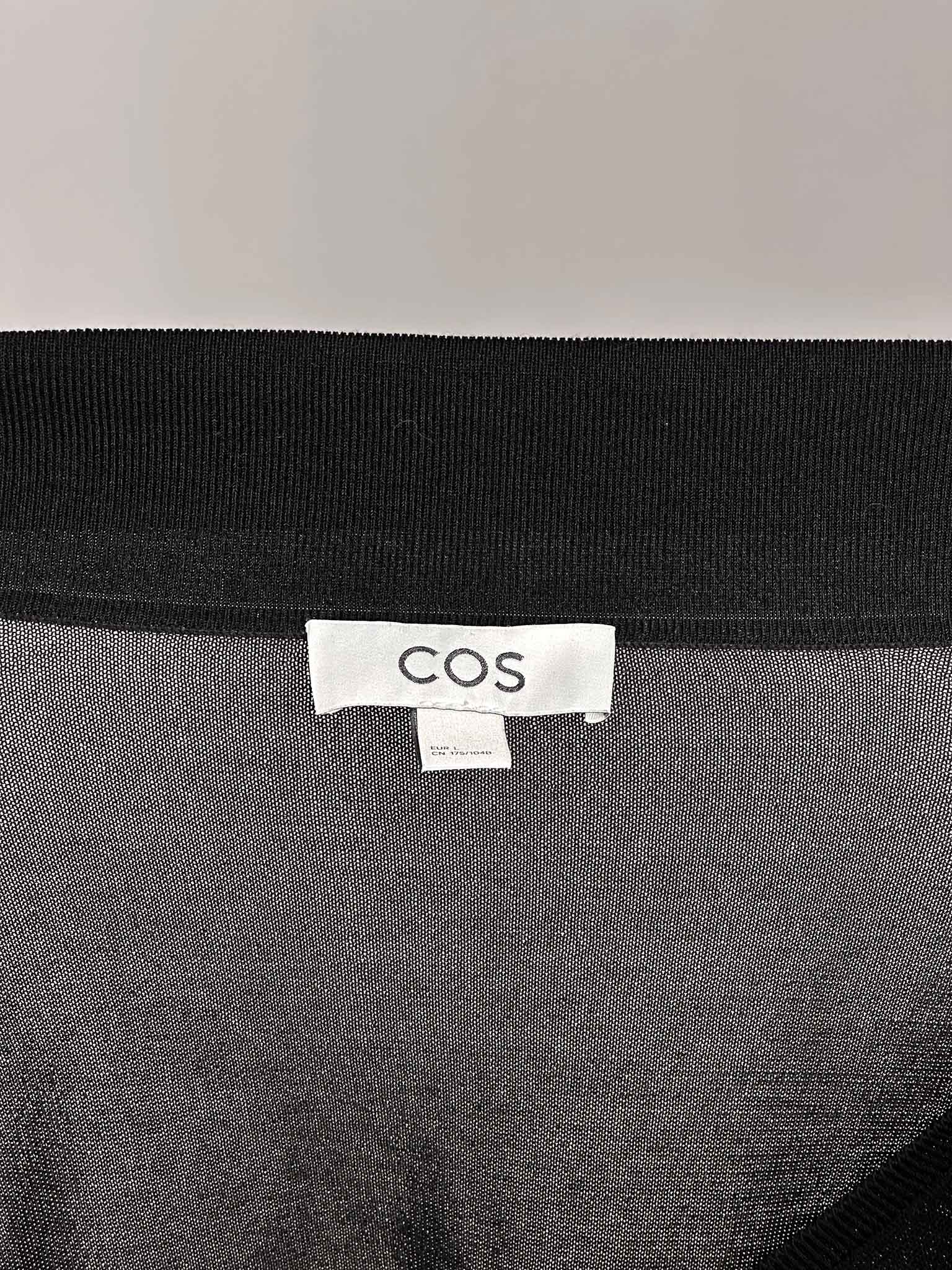 Black garment with a COS label on a gray background