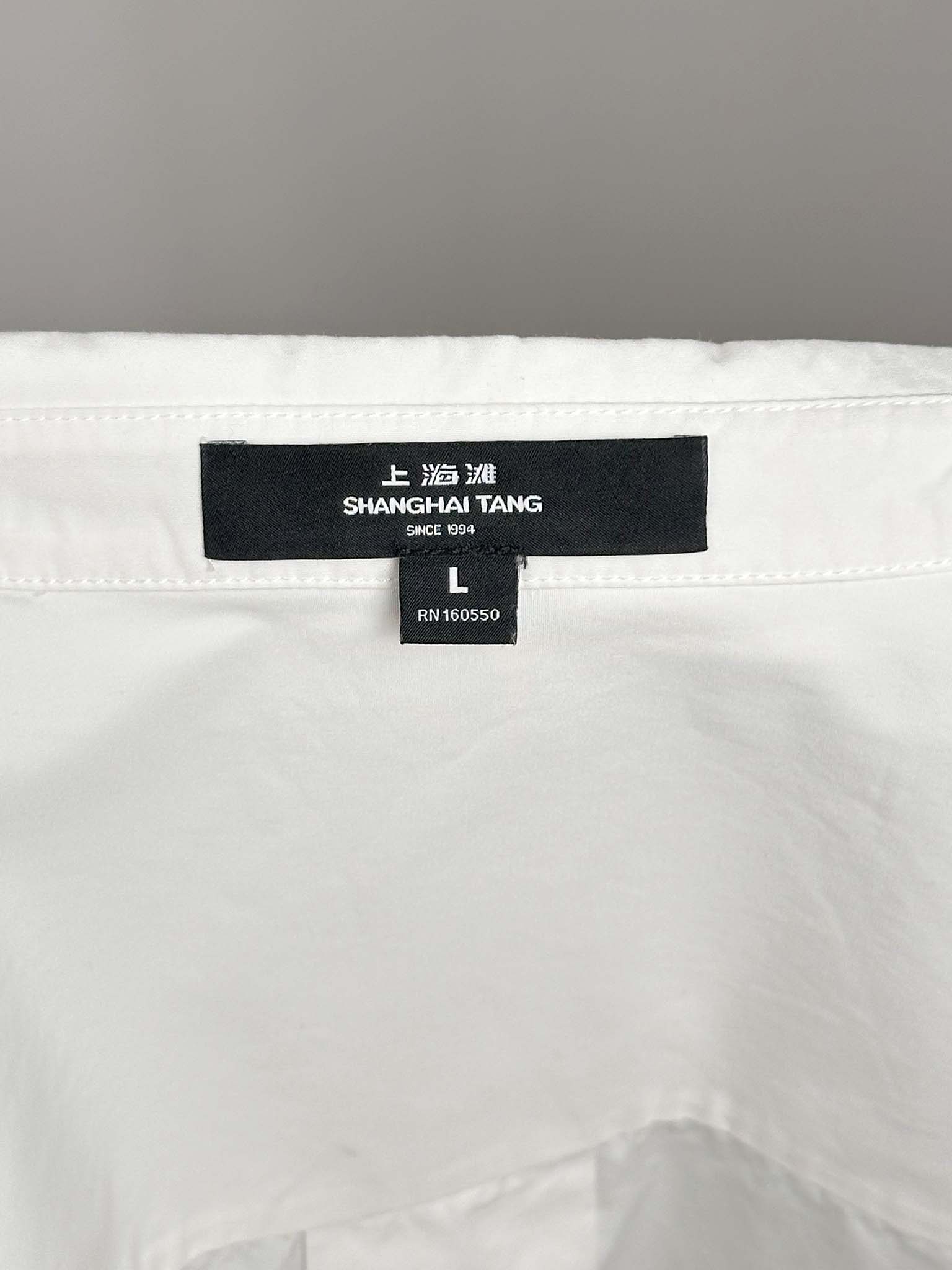 Shanghai Tang label on a white garment with a gray background