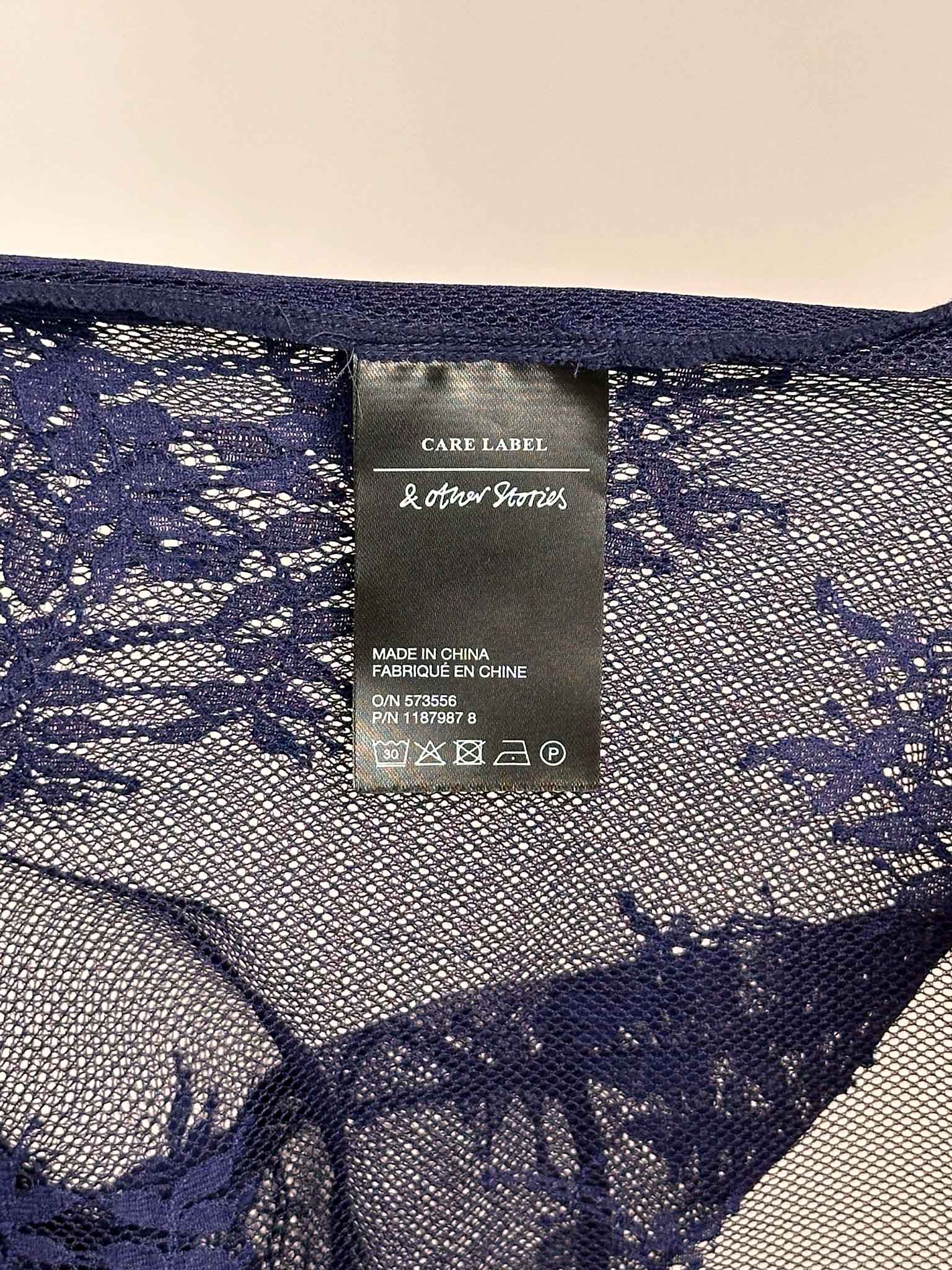 Navy lace fabric with a care & Other Stories label on a neutral background